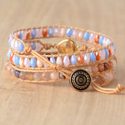 Multicolored beaded wrap bracelet with a round dark ornamental button clasp displayed on wood