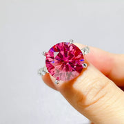 Hot pink round moissanite ring with clear side stones held close-up