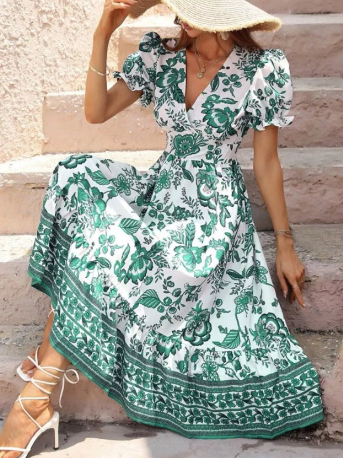 Green and white floral midi dress with puff sleeves and a border-print hem, shown seated.
