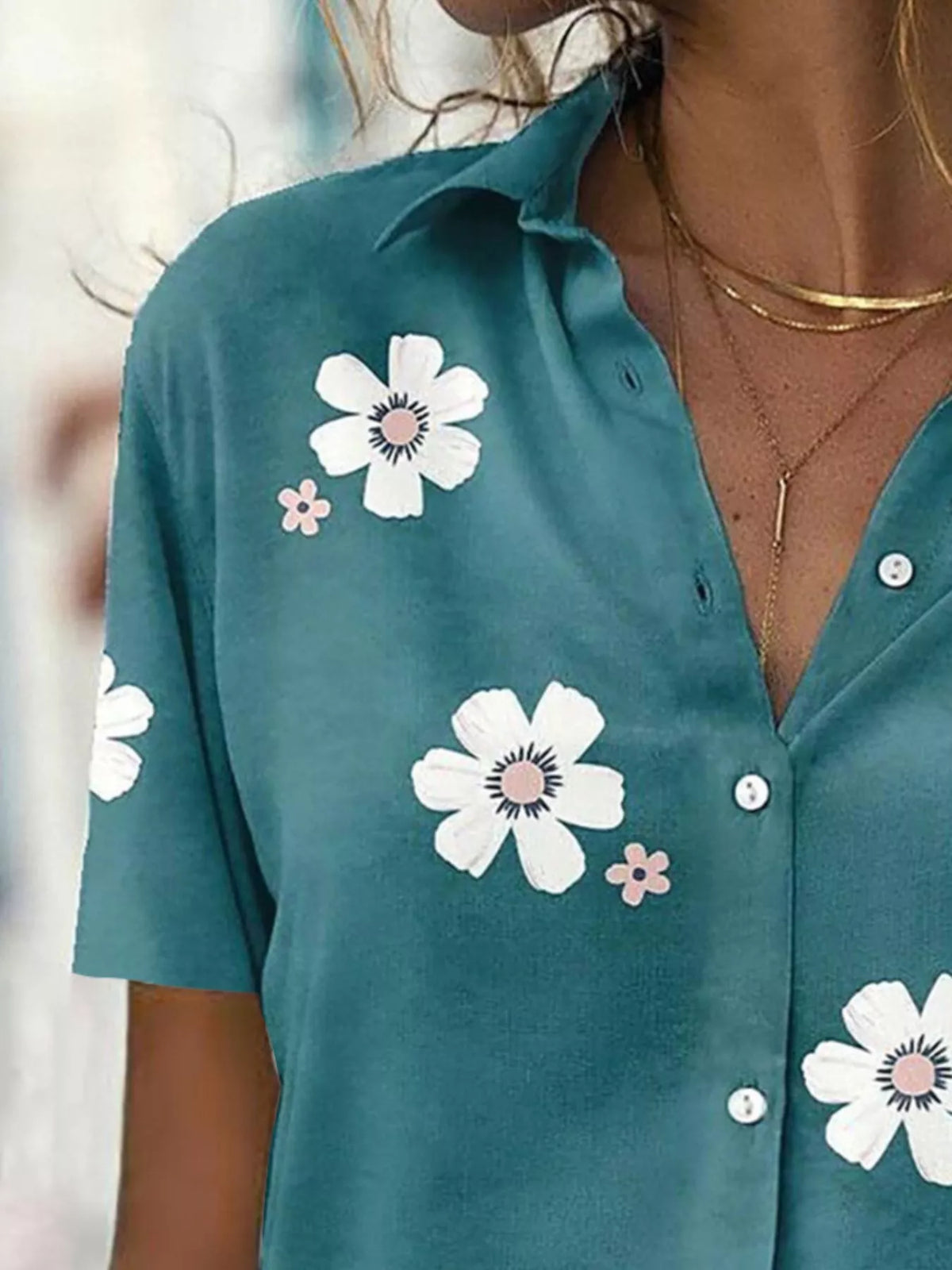 Close-up of the teal shirt's collar, buttons and white flower print.