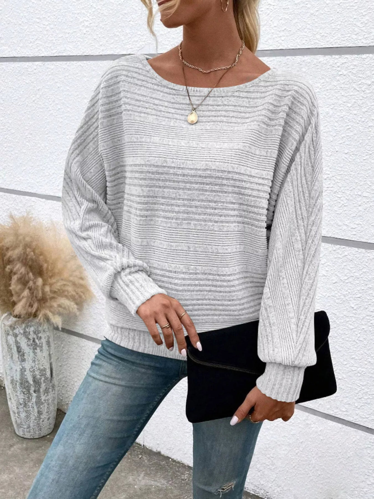 Women’s ribbed round-neck long-sleeve top in white front view with clutch at hip