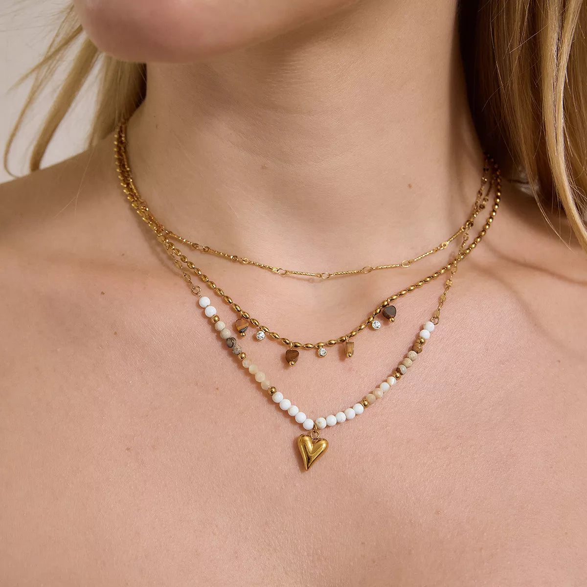 Layered gold-tone necklaces with heart pendant and white beads