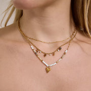 Layered gold-tone necklaces with heart pendant and white beads