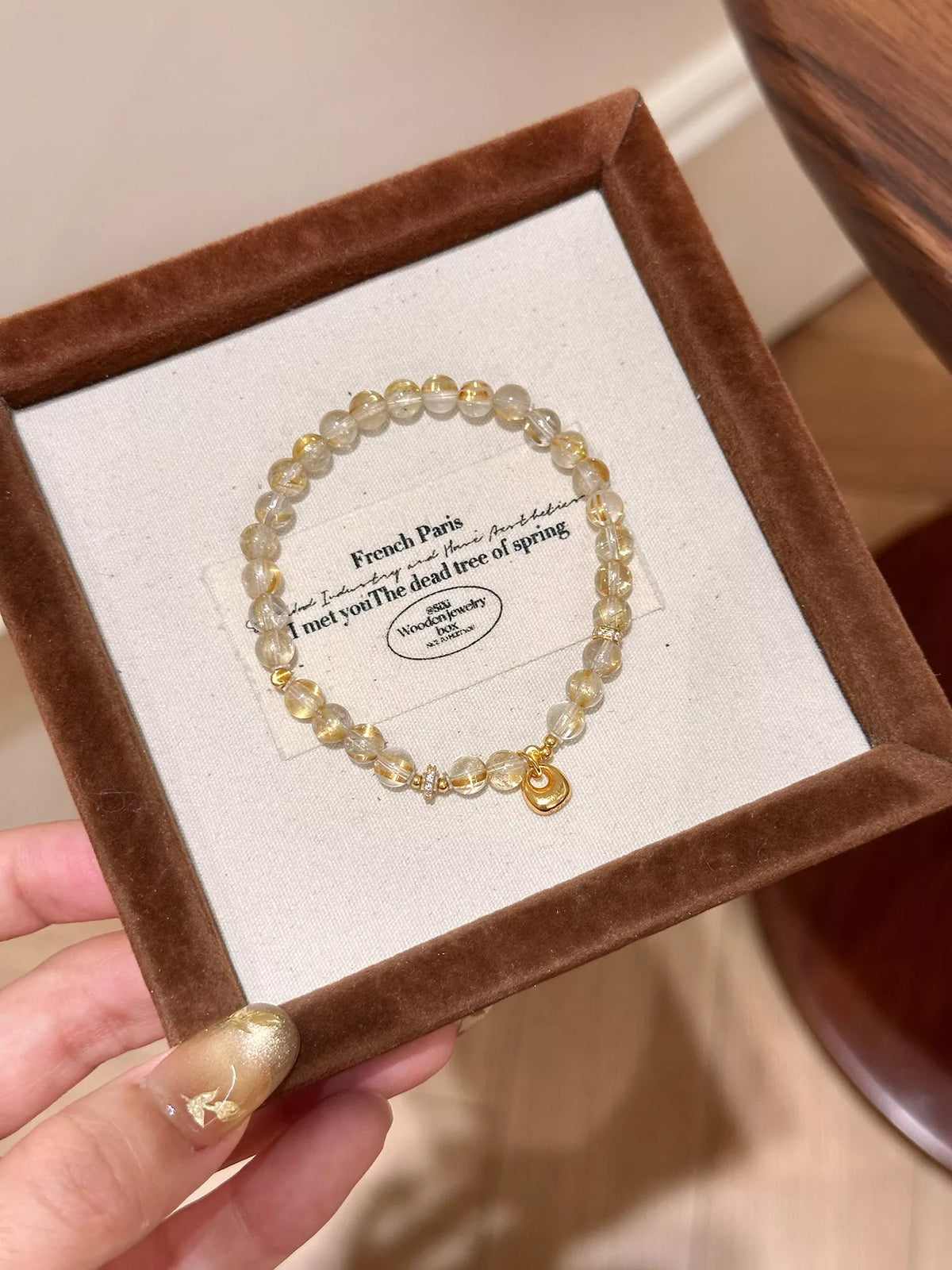 Gold-plated beaded charm bracelet presented in a square jewelry box.