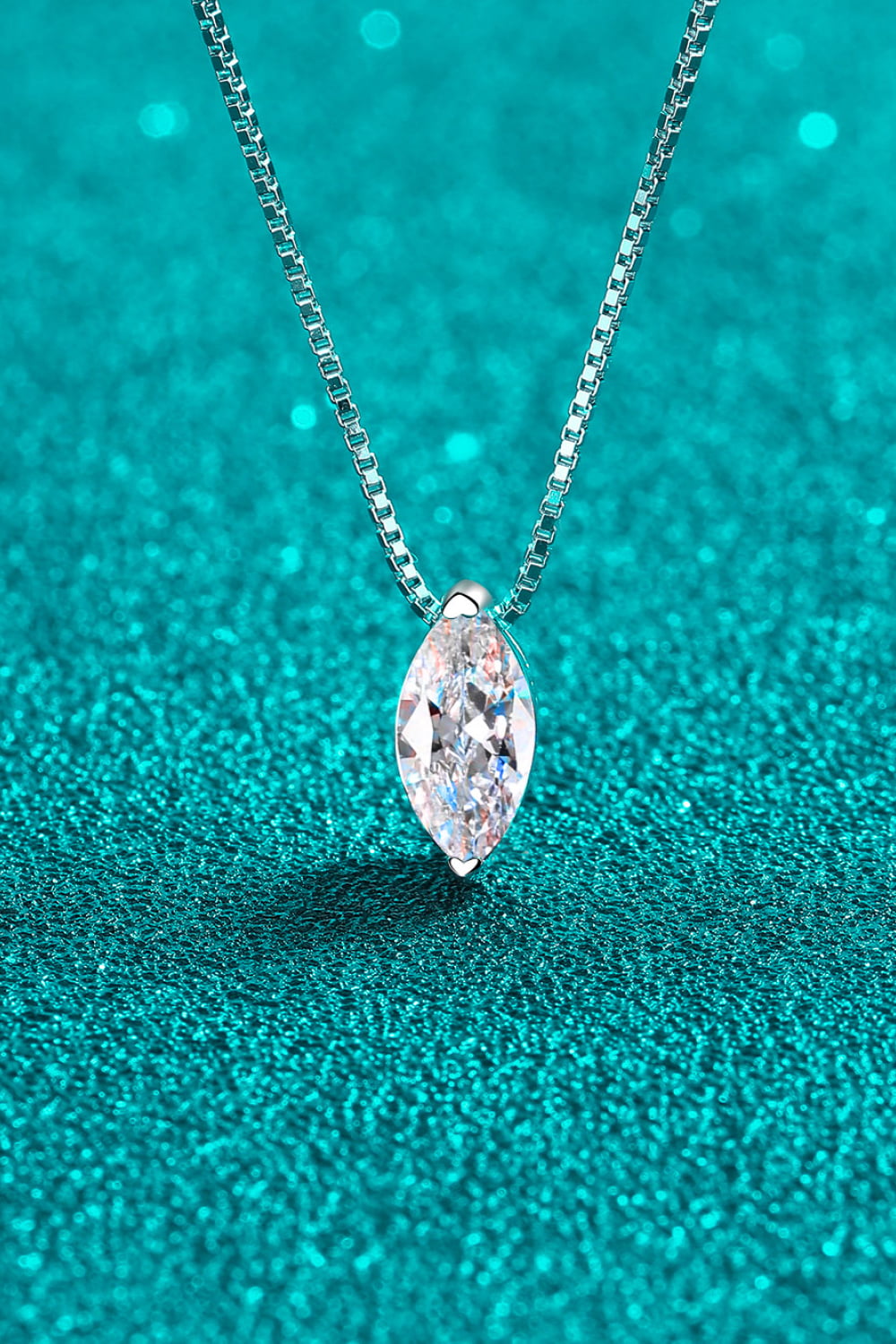 Marquise-cut moissanite pendant necklace on teal background