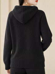 Back view of the black knit sweater showing its hood and ribbed hem.