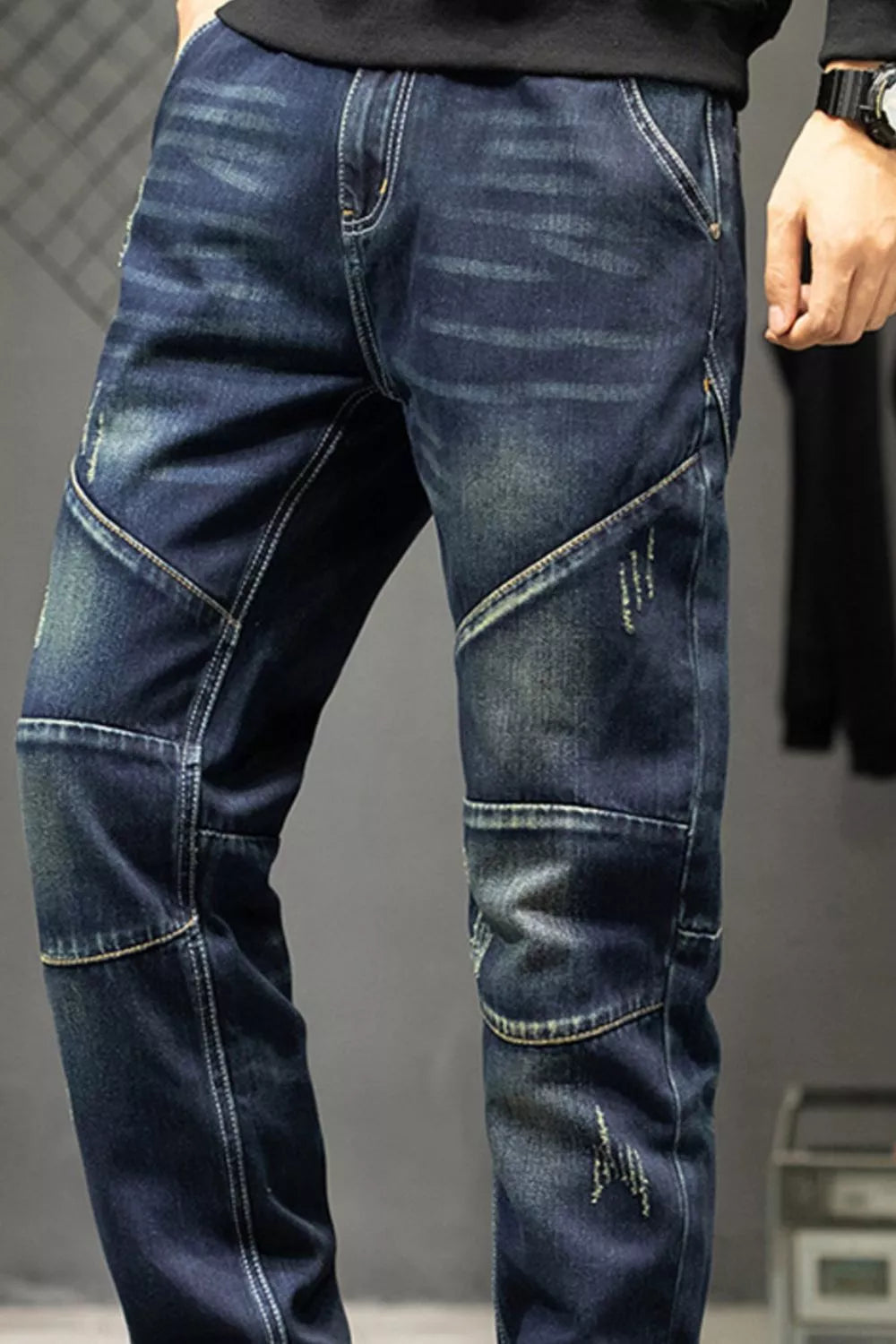 Close-up of the faded front and contrast-stitched panels on dark blue jeans