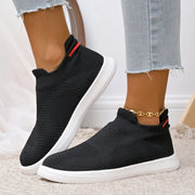 Side view of black knit slip-ons with white soles and red heel accents