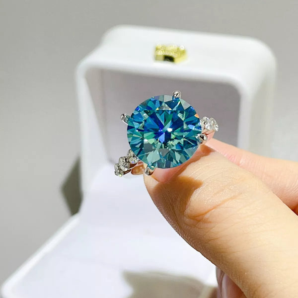 Blue-green round-stone ring held in front of an open jewellery box