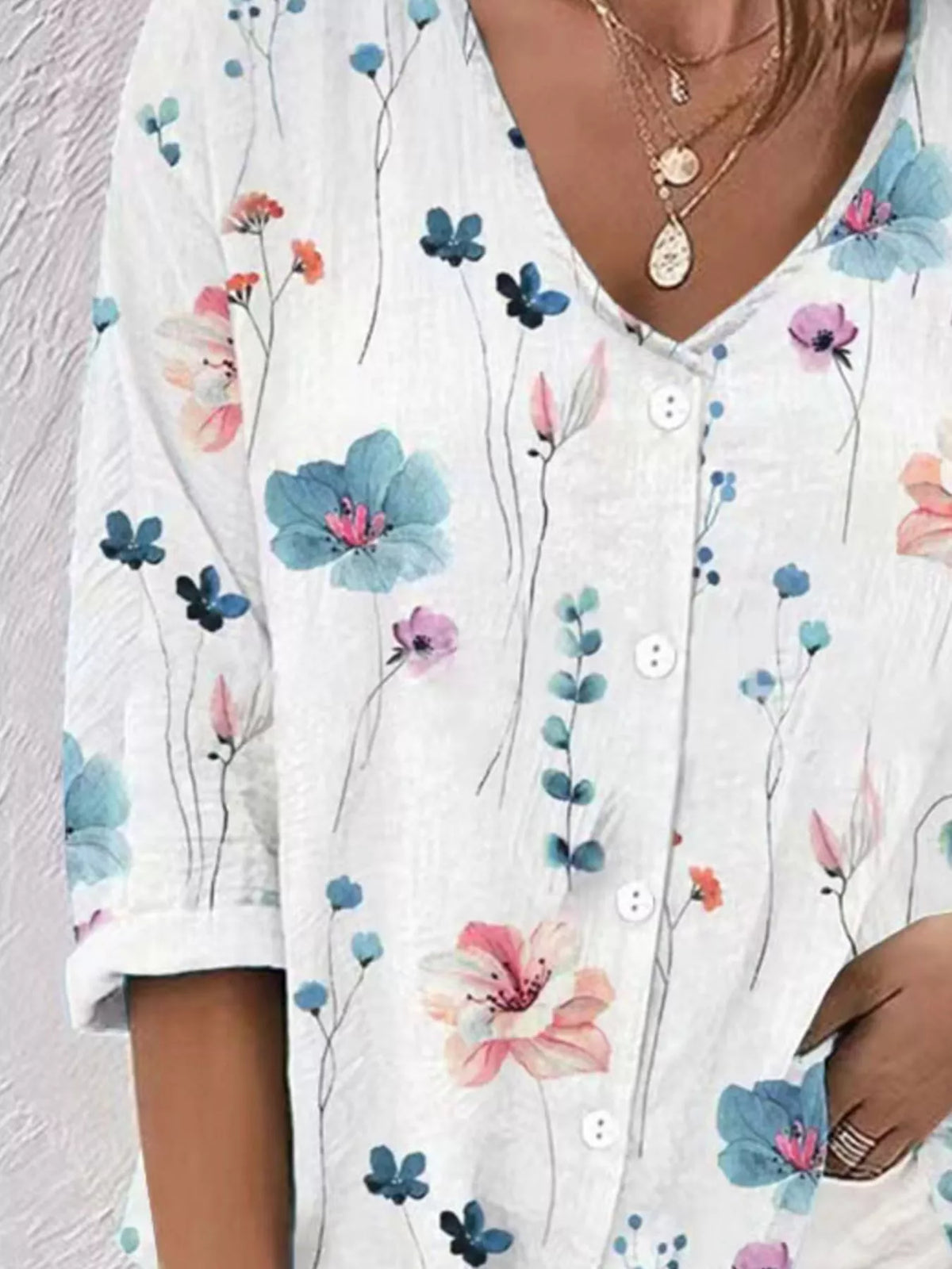 Detail view of white blouse with colorful flowers and buttons.