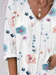 Detail view of white blouse with colorful flowers and buttons.