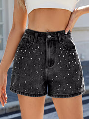 Front view of black studded denim shorts with a button waist and belt loops