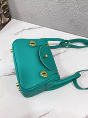 Teal crossbody bag lying on its side, showing bottom and gold-tone feet