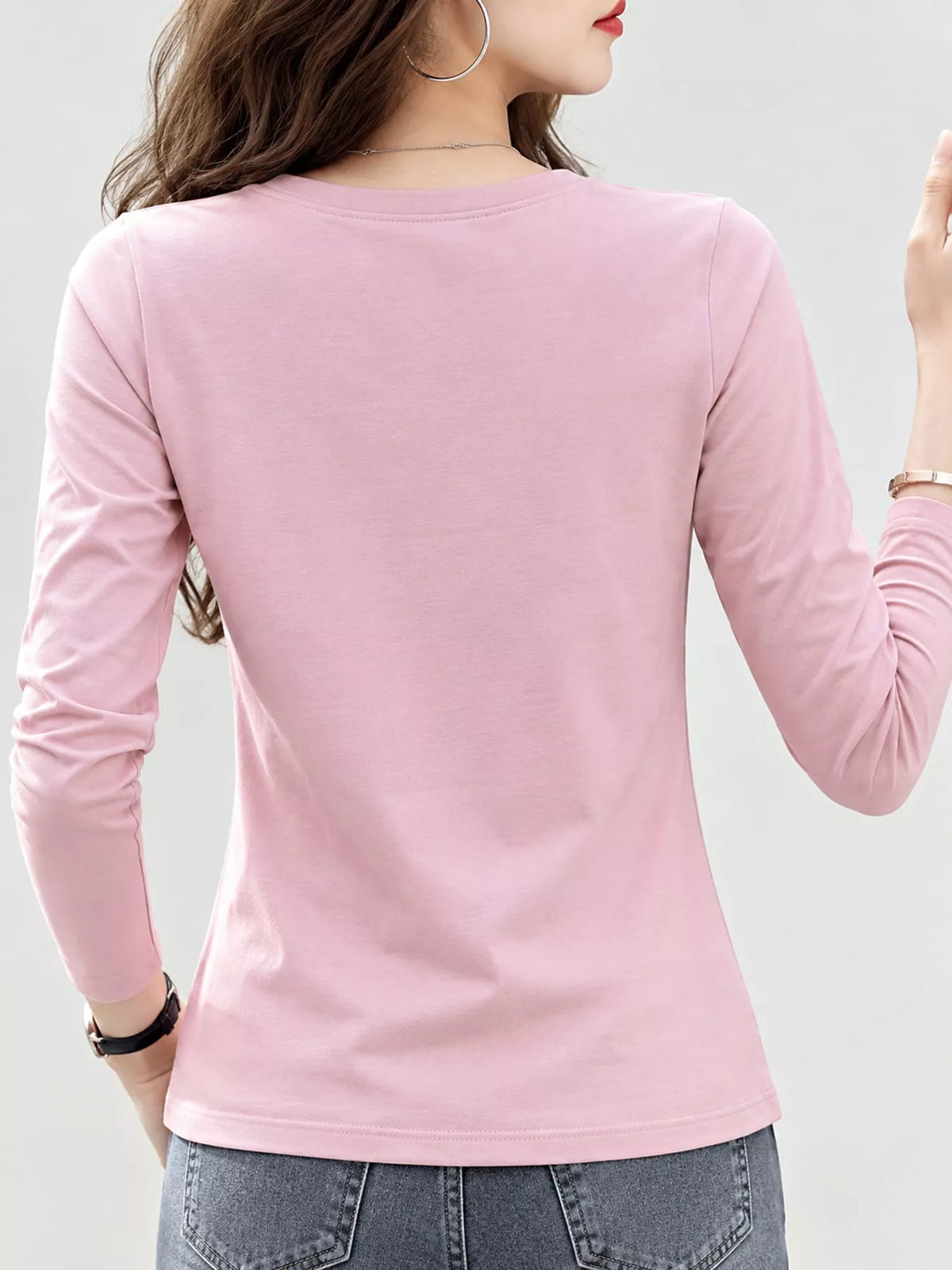 Back view of a pink long-sleeve T-shirt worn with jeans.