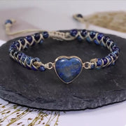 Navy and gold-tone adjustable bracelet with a blue heart, angled on a dark slate display.