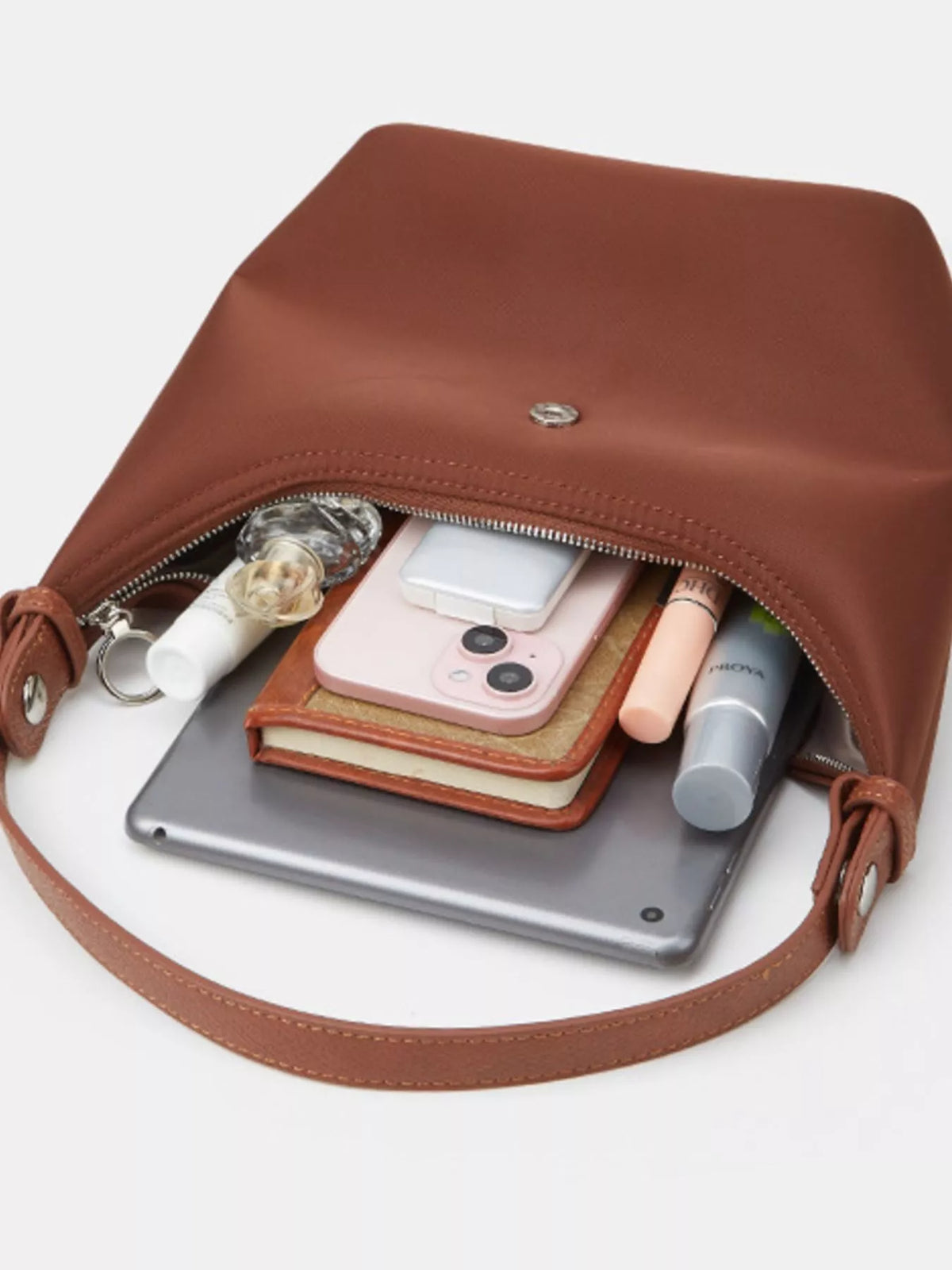 Close-up of the open brown bag with a phone and small personal items beside its interior.