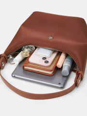 Close-up of the open brown bag with a phone and small personal items beside its interior.