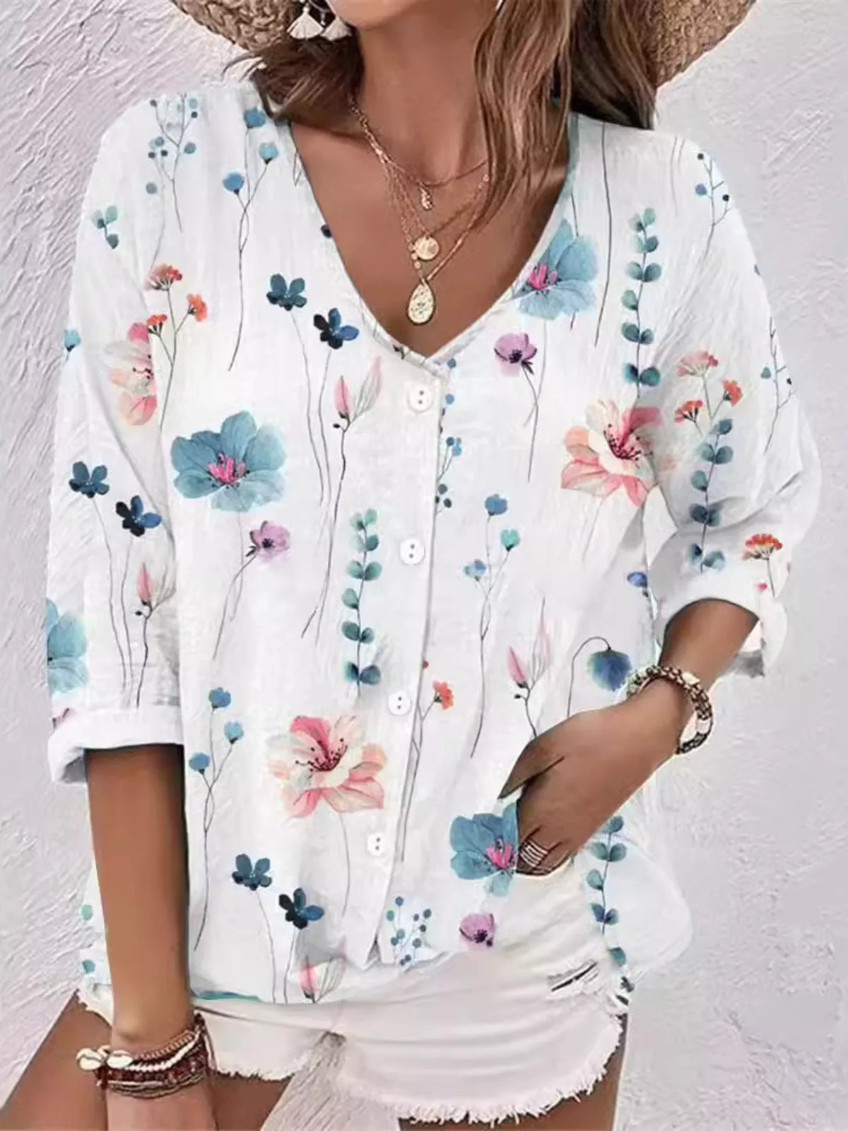 Model wearing white blouse with multicolor floral print and white shorts.