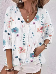 Model wearing white blouse with multicolor floral print and white shorts.