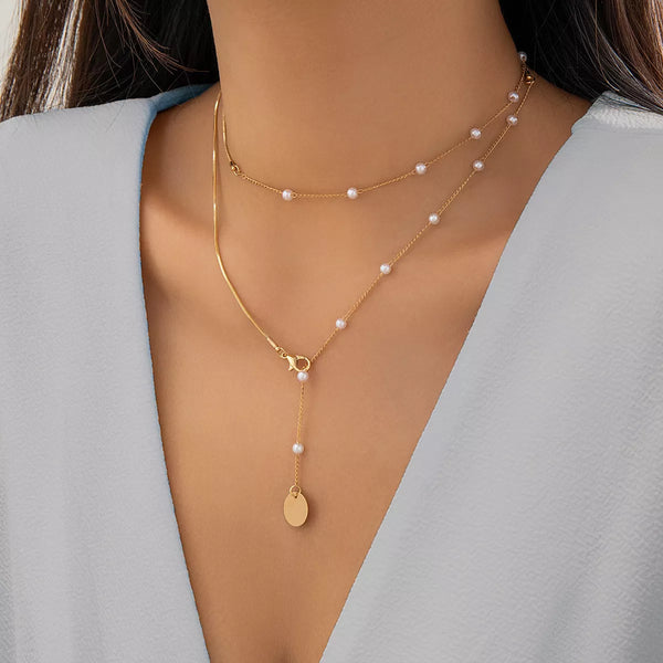 Gold-tone layered pearl station necklace with round coin pendant worn on a model