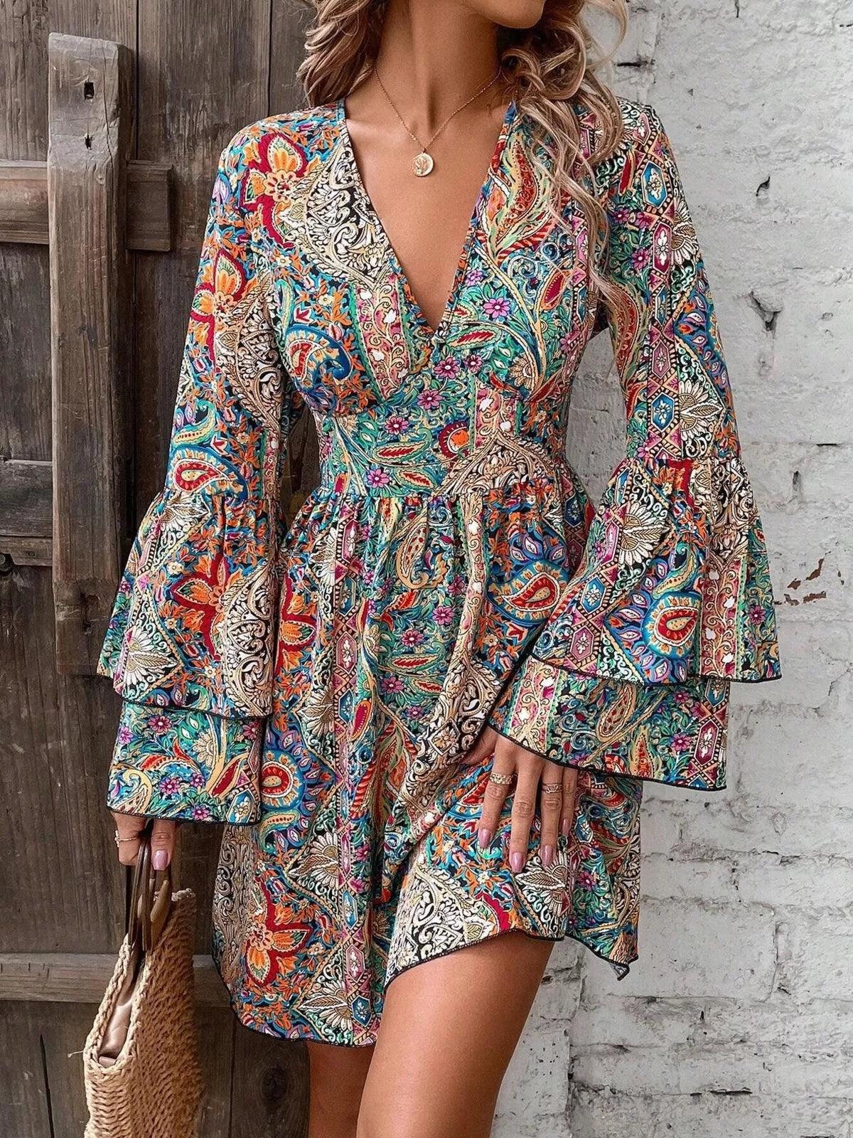 Model wearing colorful paisley V-neck mini dress with bell sleeves, front view