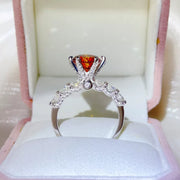 Front view of a three-carat red-orange moissanite ring in an open white box