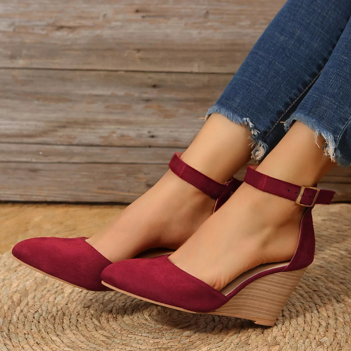 Burgundy pointed-toe wedge sandals shown from the side on feet