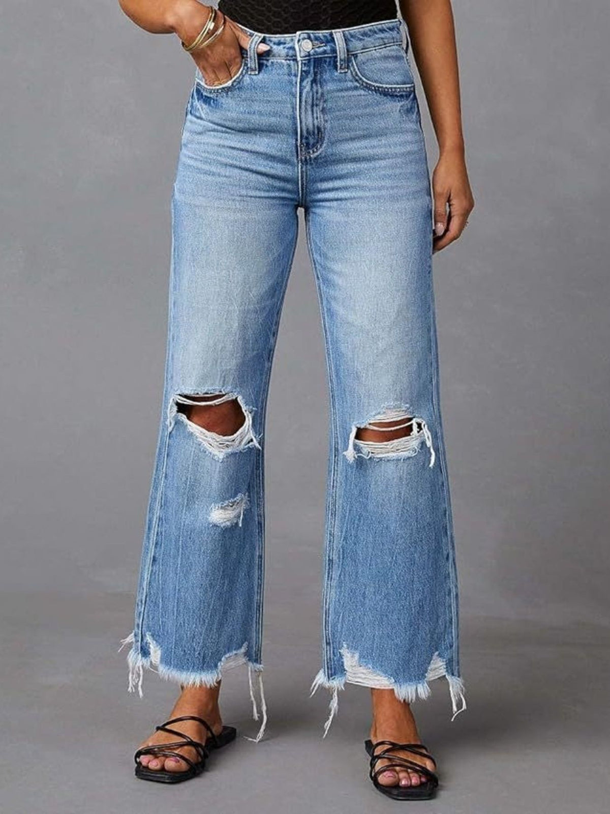 Close front view of flared jeans with rips at both knees.
