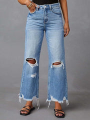 Close front view of flared jeans with rips at both knees.