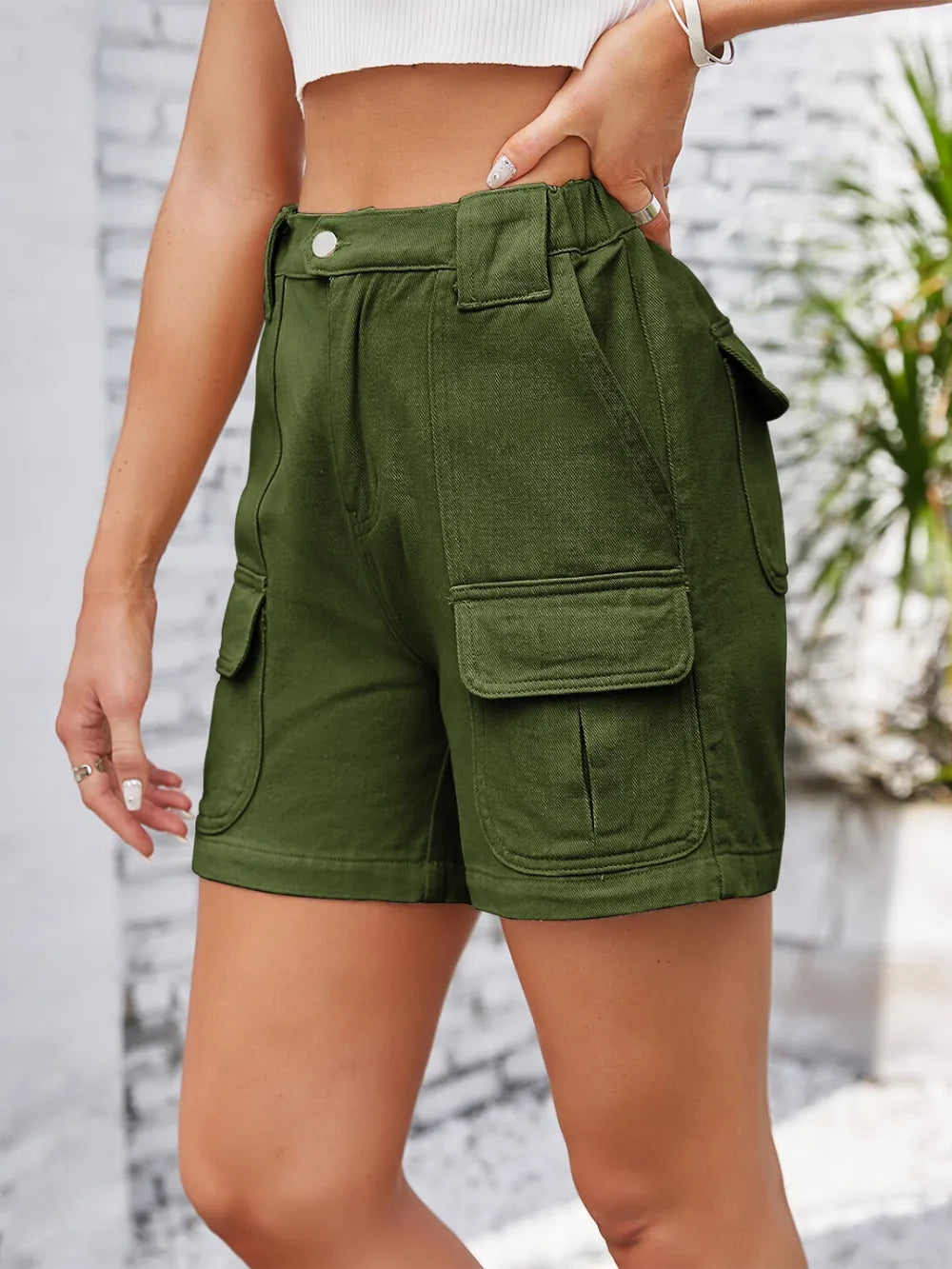 Side view of olive cargo shorts with large flap pocket.