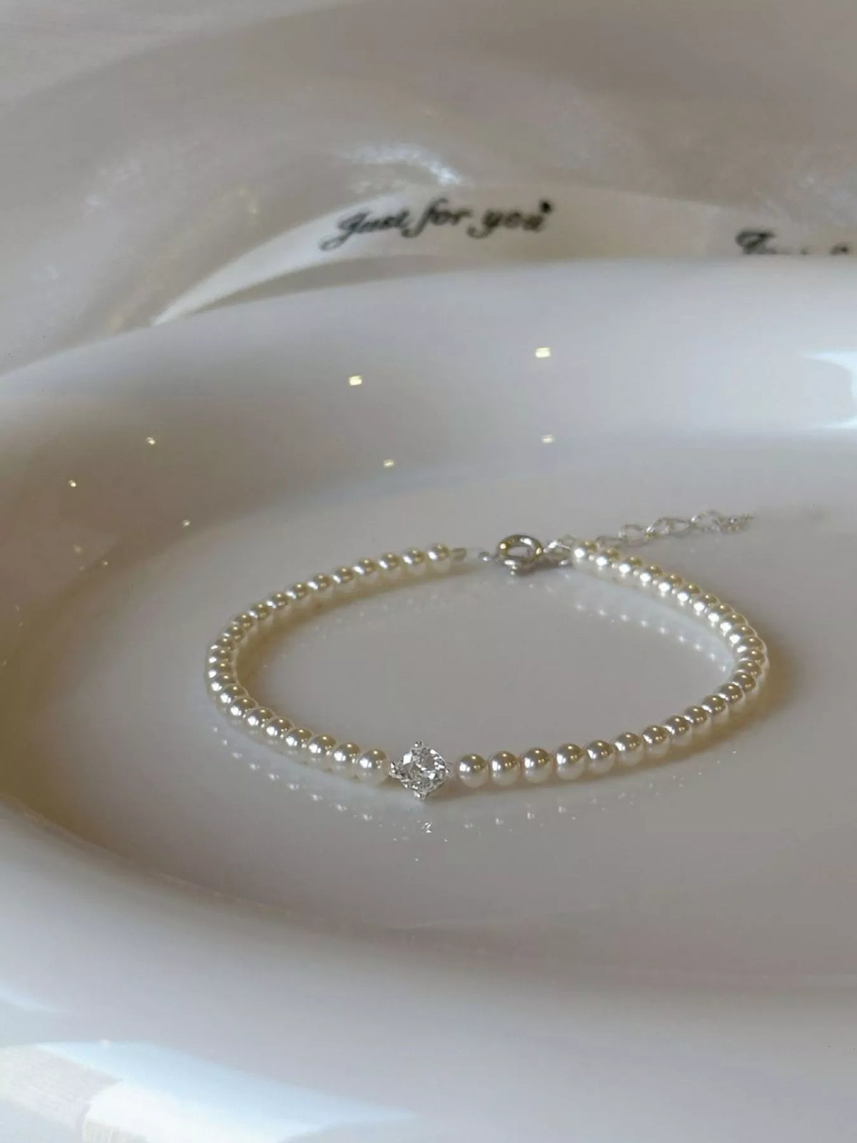 Circular pearl bracelet displayed on a white satin surface.