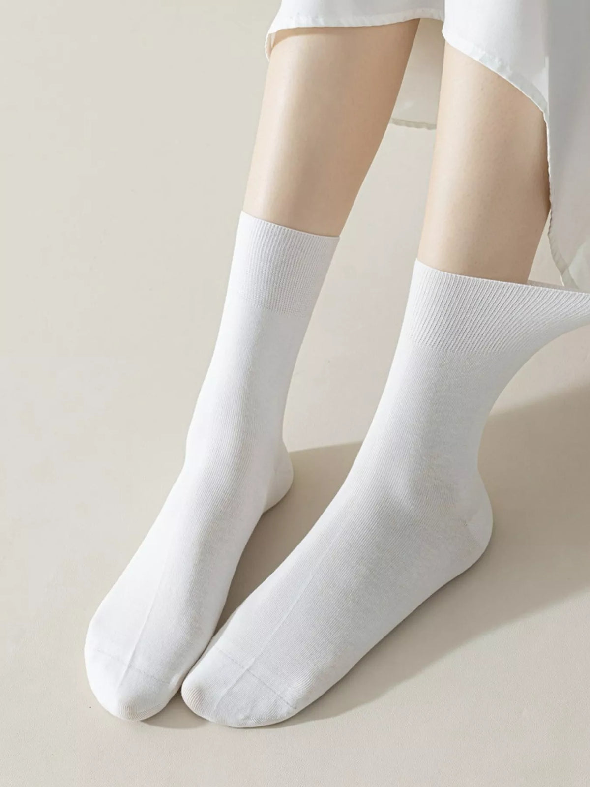 Pair of plain white mid-calf socks displayed on feet