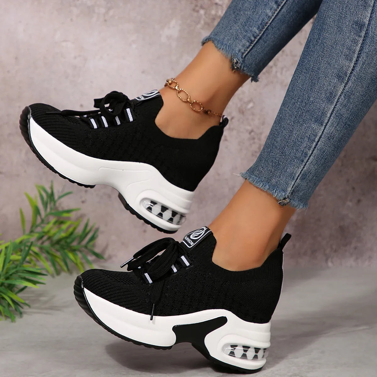 Black lace-up platform sneakers worn with blue jeans, angled side view
