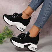 Black lace-up platform sneakers worn with blue jeans, angled side view