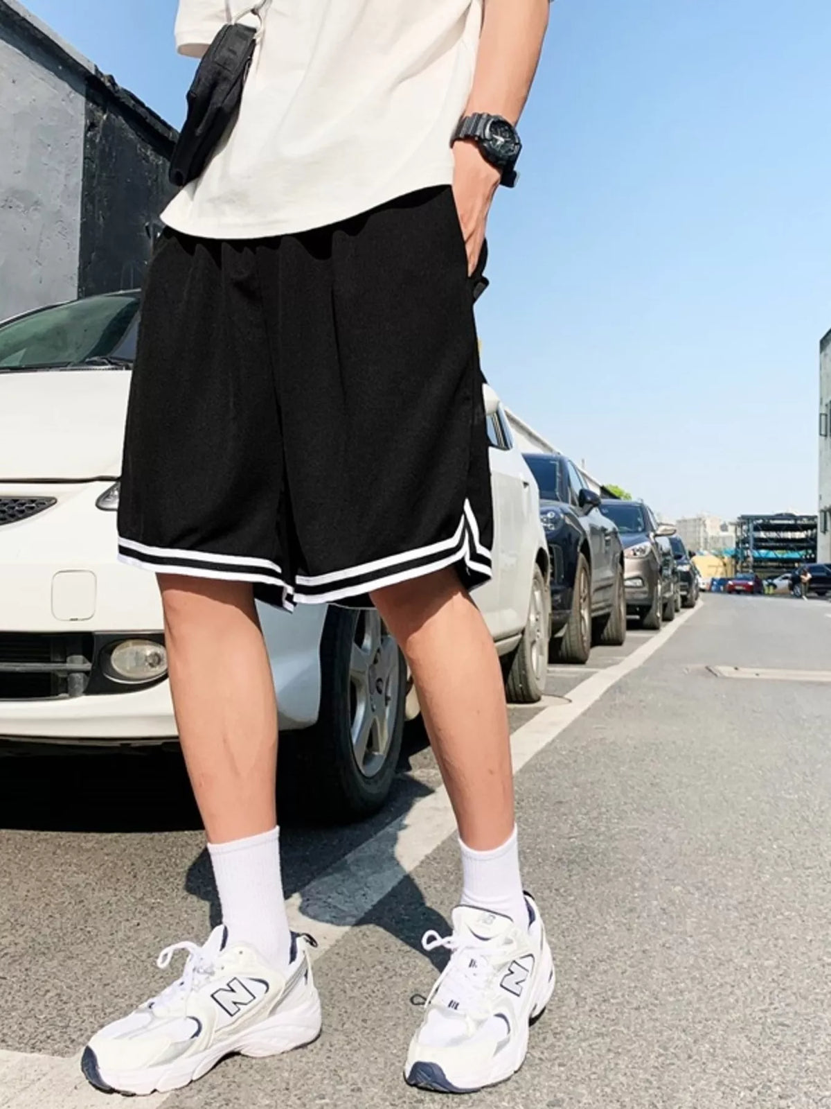 Model wearing black basketball shorts with white striped trim