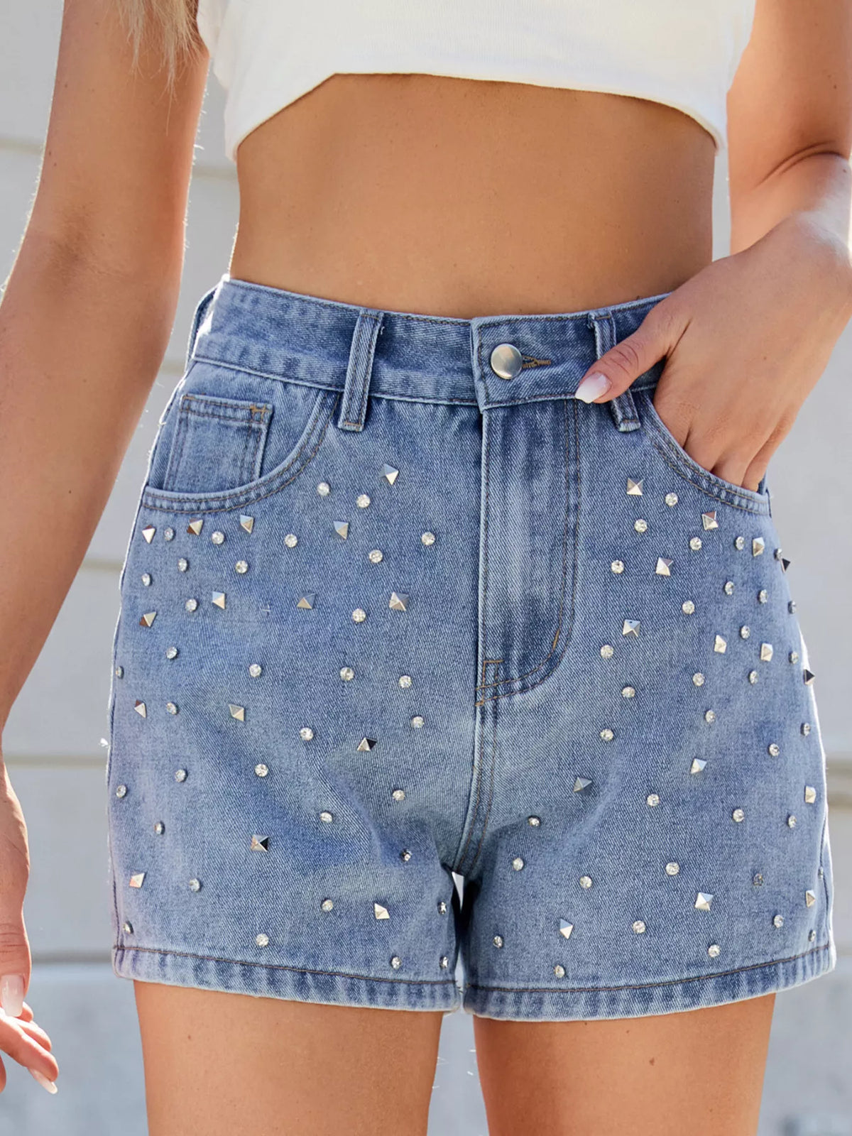 Close front view of blue high-waisted shorts showing round and square studs around the pockets