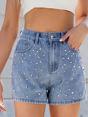 Close front view of blue high-waisted shorts showing round and square studs around the pockets