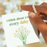 Close-up of daisy flower band ring beside floral message card