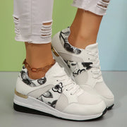 White sneakers with black floral panels worn with ankle bracelets