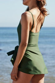 Side-back view of the sage-green swim dress, showing the wide straps and flared skirt.