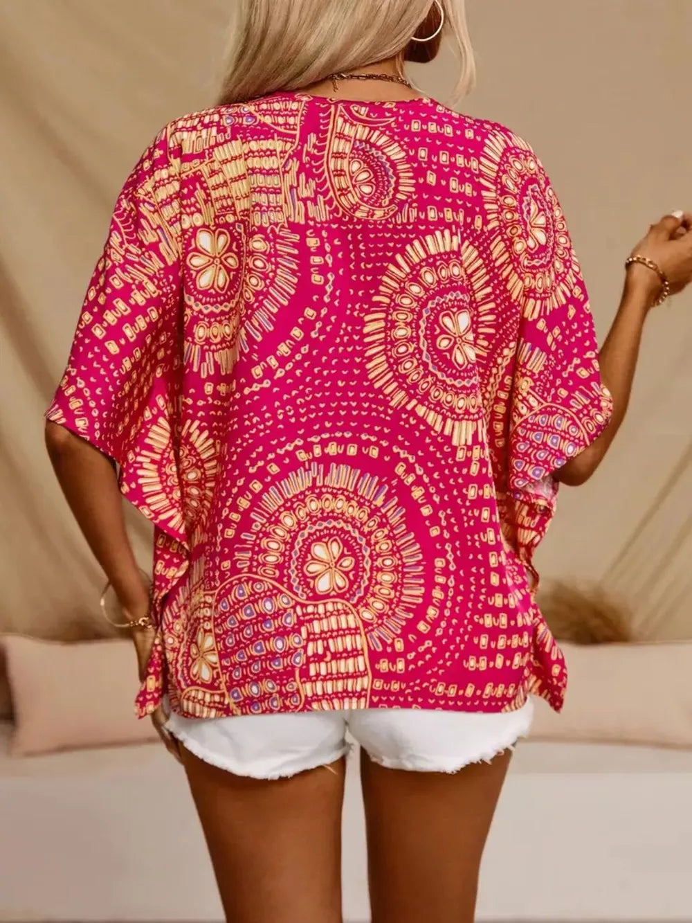 Back view of a pink and yellow medallion-print blouse with loose half sleeves.