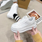 White platform sneakers held in hands, side view