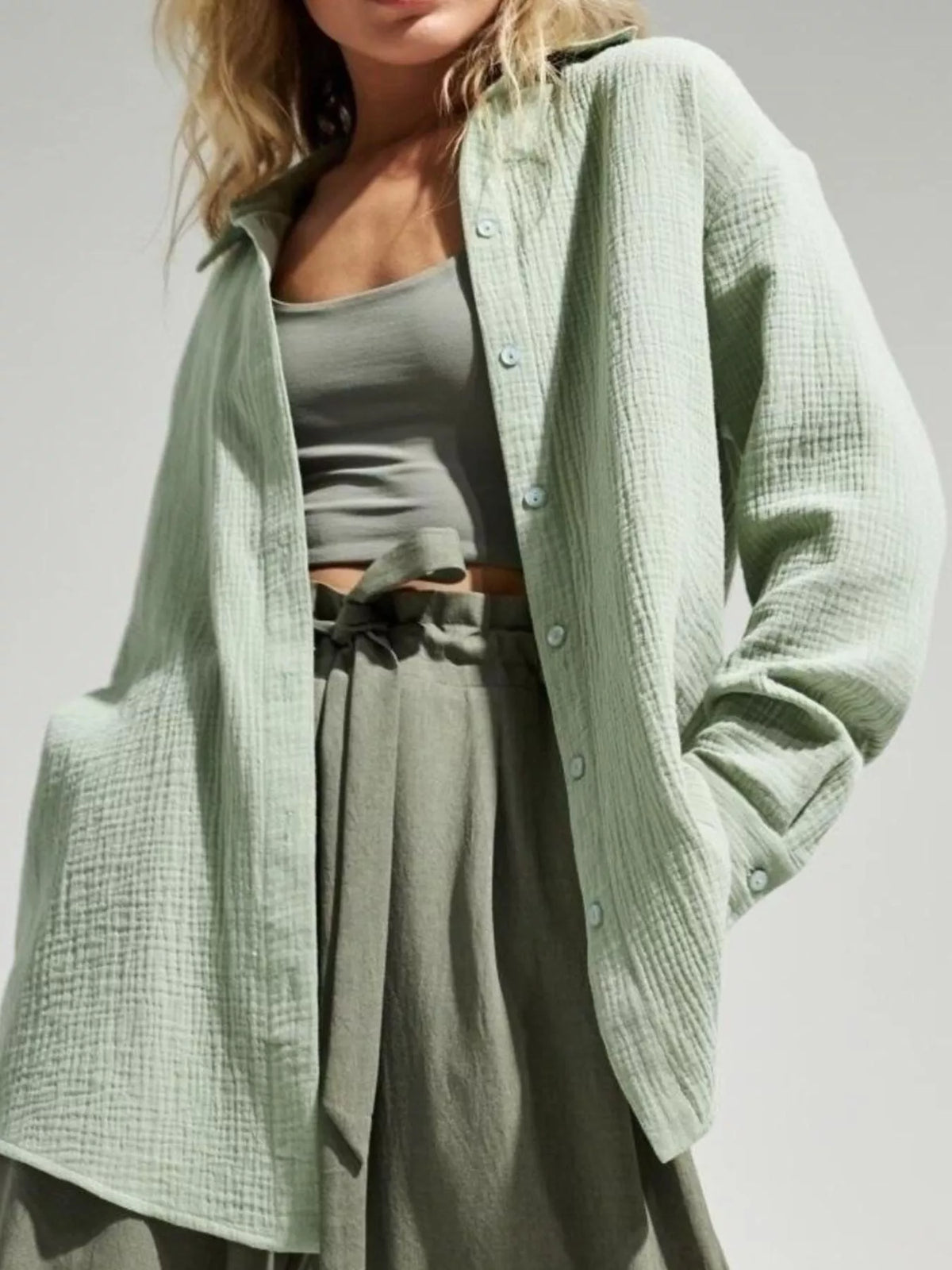 Model in pale green textured gauze shirt with neutral trousers.