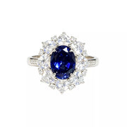 Close-up of an oval blue center stone and surrounding clear stones on a silver-tone ring