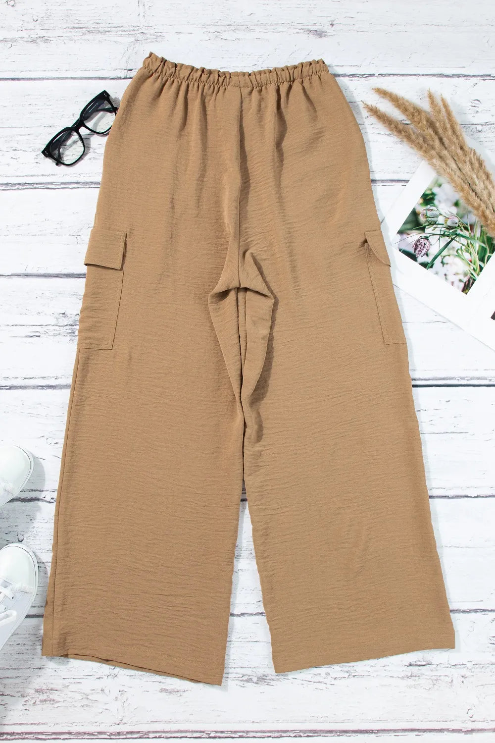 Back of tan utility trousers laid flat with wide straight legs