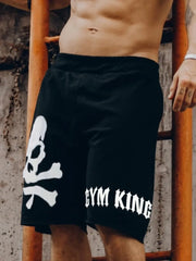 Model wearing black graphic drawstring shorts with skull and text print