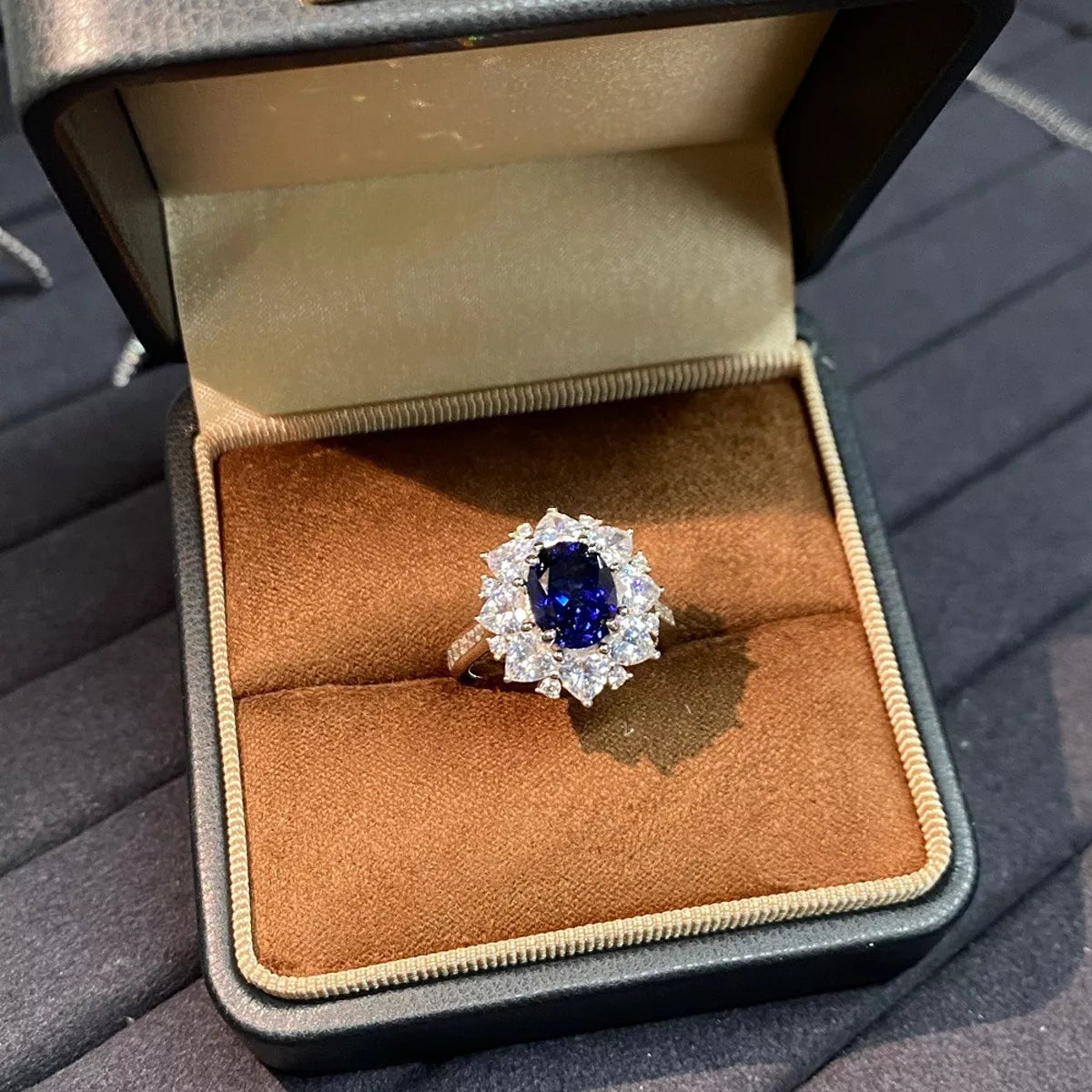 Royal-blue oval sapphire ring centered in an open tan jewelry box