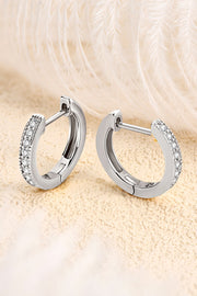 Pair of stone-set silver hoop earrings displayed open against a soft textured background