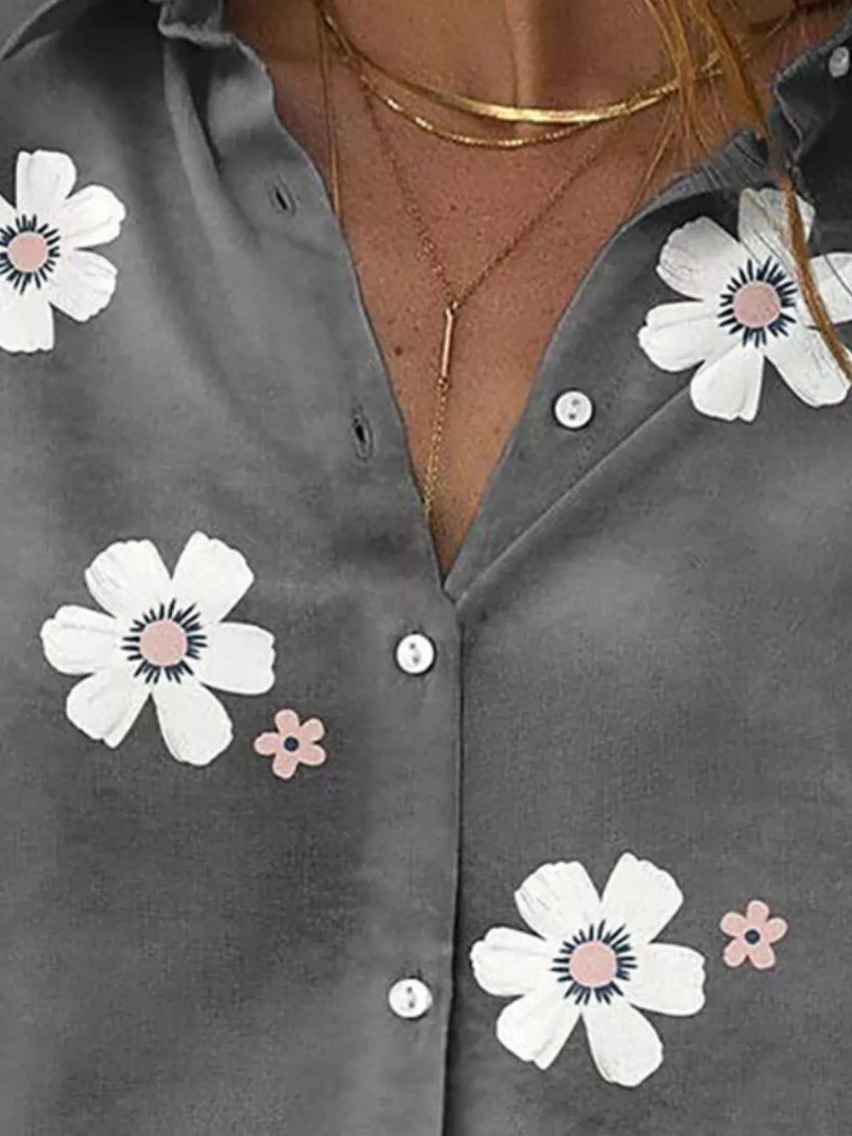 Close-up of white flower motifs and the collar opening on the charcoal shirt.