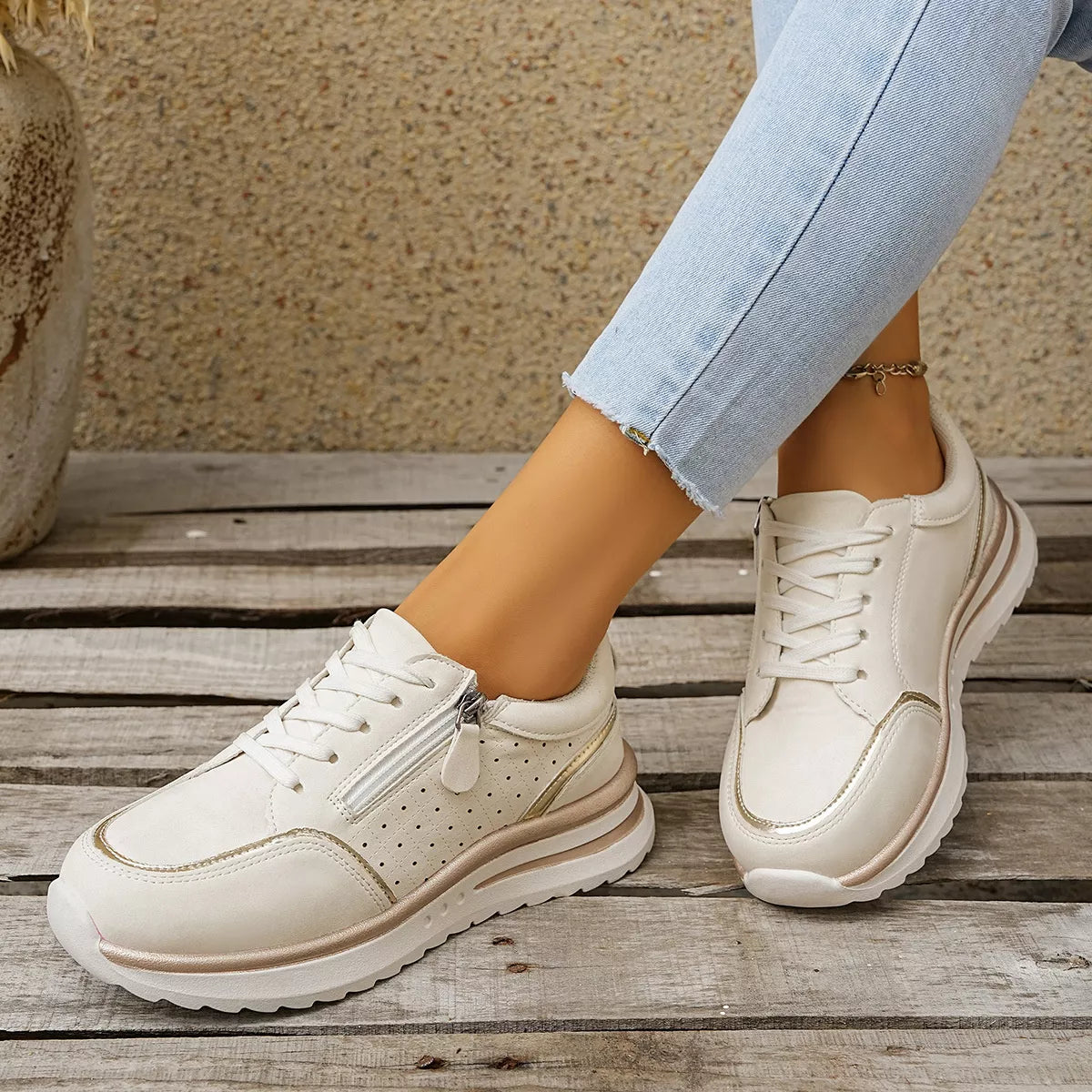 Pair of white sneakers held to show side panels